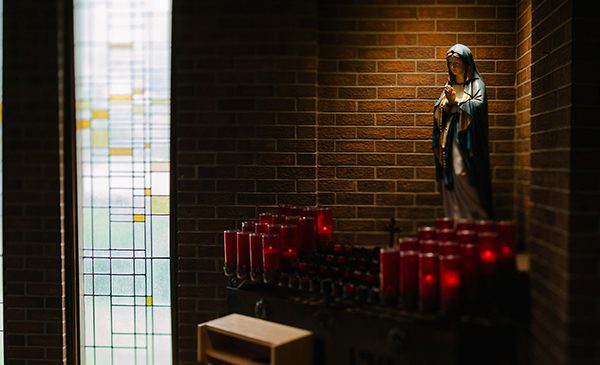 a chapel with lit candles in front of a statue of the Virgin Mary